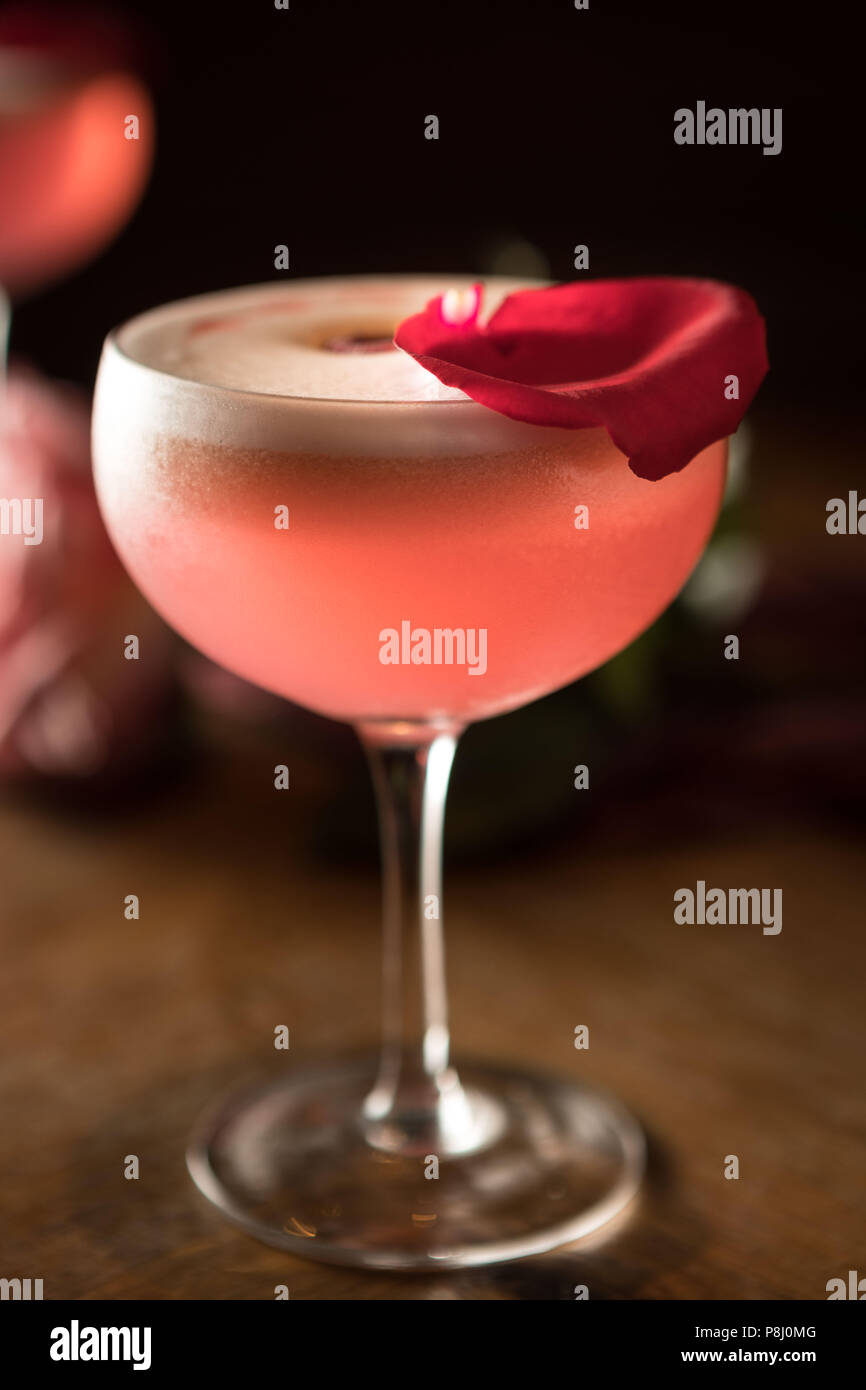 Cocktail de Saint-Valentin rose à base de gin, léger et rafraîchissant avec pétales de rose comme garniture. Banque D'Images