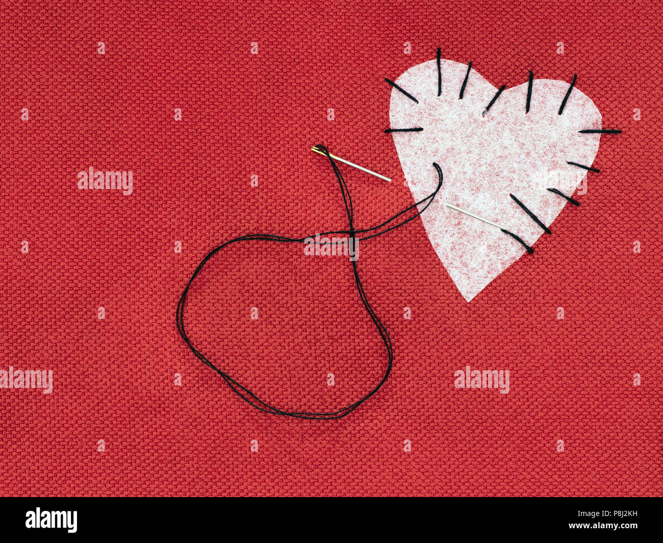Coeur en tissu rouge avec tache blanche et noire du fil à coudre. Mend broken heart concept. Banque D'Images