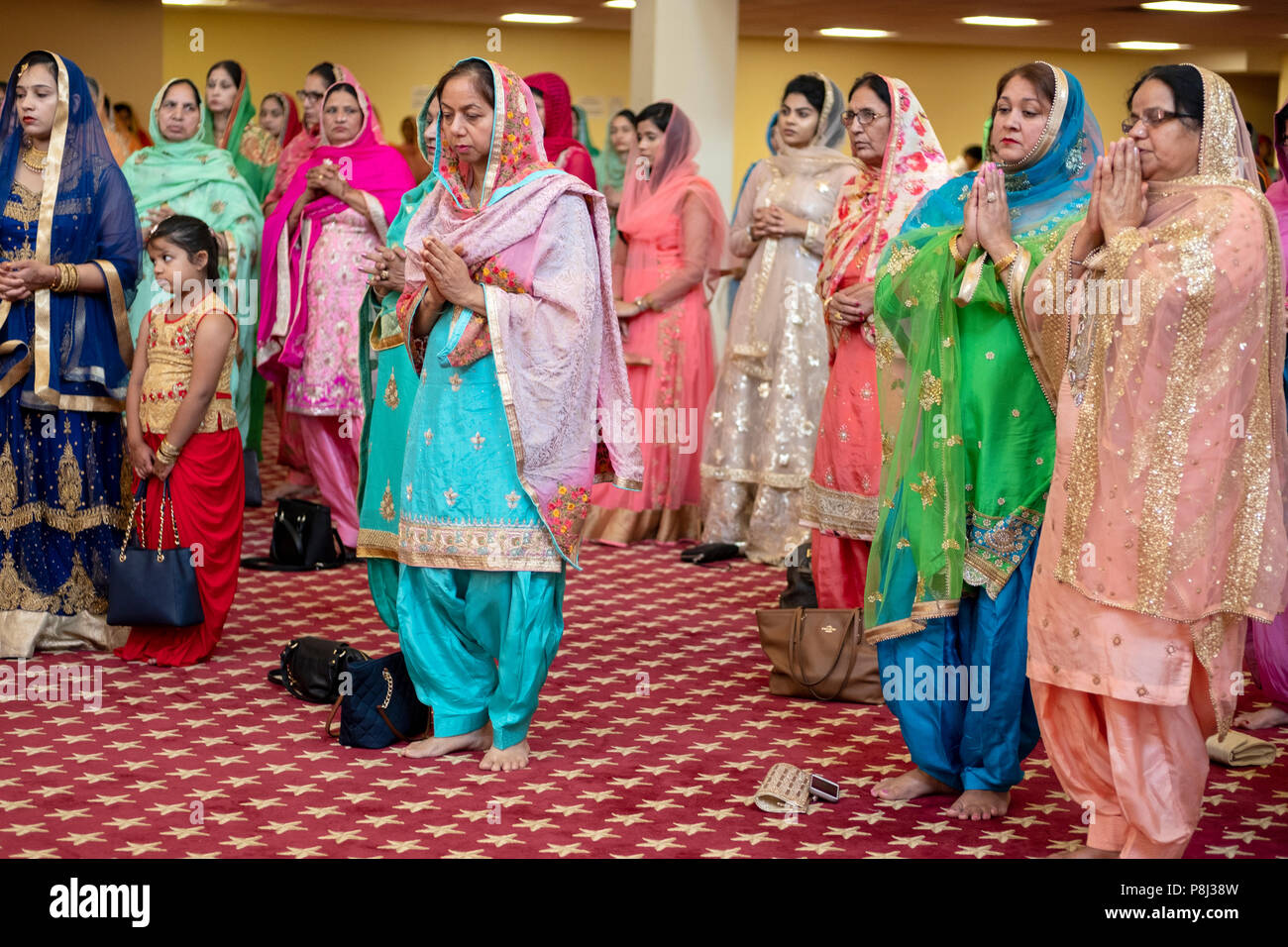 Un groupe de femmes priant et méditant comme invités à une cérémonie de mariage dans le temple à la Sikh Society à Richmond Hill, Queens, New York. Banque D'Images