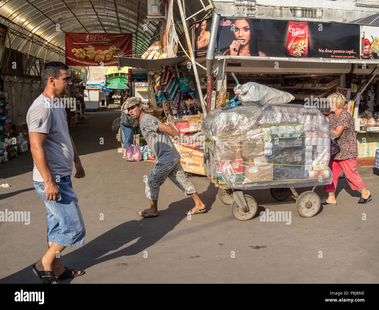 CHISINAU, MOLDOVA - 11 août 2015 : Deux livreurs, un homme et une femme, montrant les efforts visant l'extraction d'un panier au marché central de la capitale Banque D'Images CHISINAU, MOLDOVA - 11 août 2015 : Deux livreurs, un homme et une femme, montrant les efforts visant l'extraction d'un panier au marché central de la capitale Banque D'Images