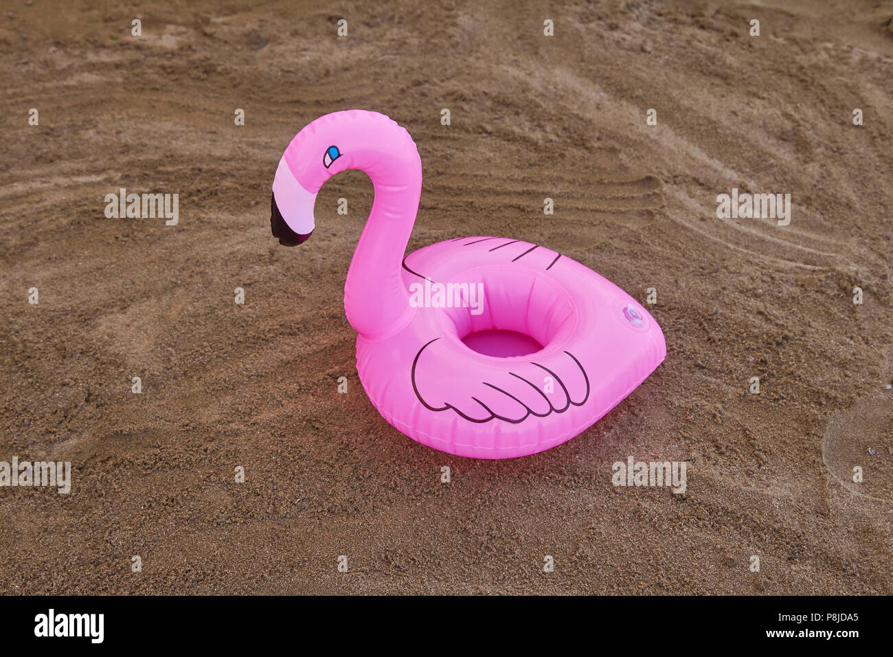 Porte-verre flamingo gonflable sur la plage de sable dans une journée ensoleillée de l'été. Banque D'Images