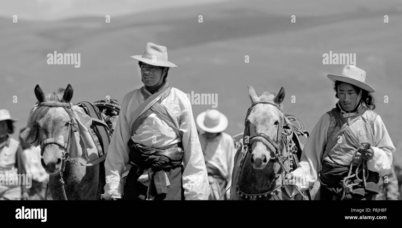 Khampas à pied leurs chevaux retour à la ligne de départ à l'Litang Horse Festival - Kham, province du Sichuan, Chine (Tibet), Banque D'Images