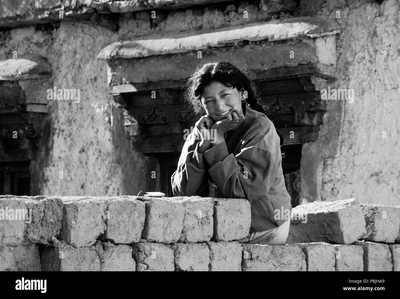 Beautiful SMILING GIRL LADAKHIS (jeune femme) assis sur des briques d'ADOBE - LADAKH, INDE Banque D'Images