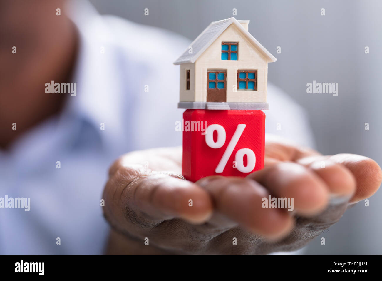 Close-up of a person's Hand Holding Miniature House sur bloc Pourcentage rouge Banque D'Images
