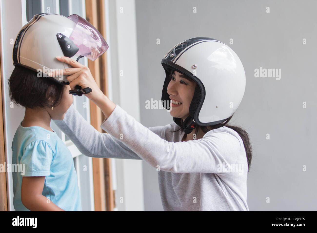 Maman aider sa fille à porter le casque avant de monter un vélo de moteur Banque D'Images