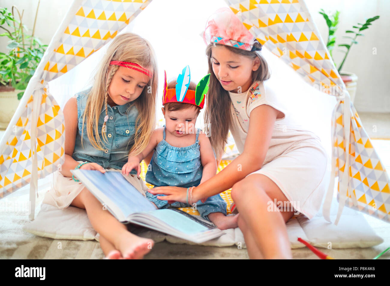 Trois jolie fille jouer et lire ensemble à l'intérieur Banque D'Images