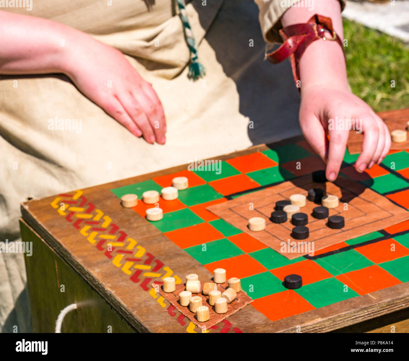 Foire Médiévale, le Palais de Linlithgow, Ecosse, Royaume-Uni. La journée de plaisir en famille divertissement d'été ; la femme en costume médiéval joue neuf mens Morris jeu Banque D'Images