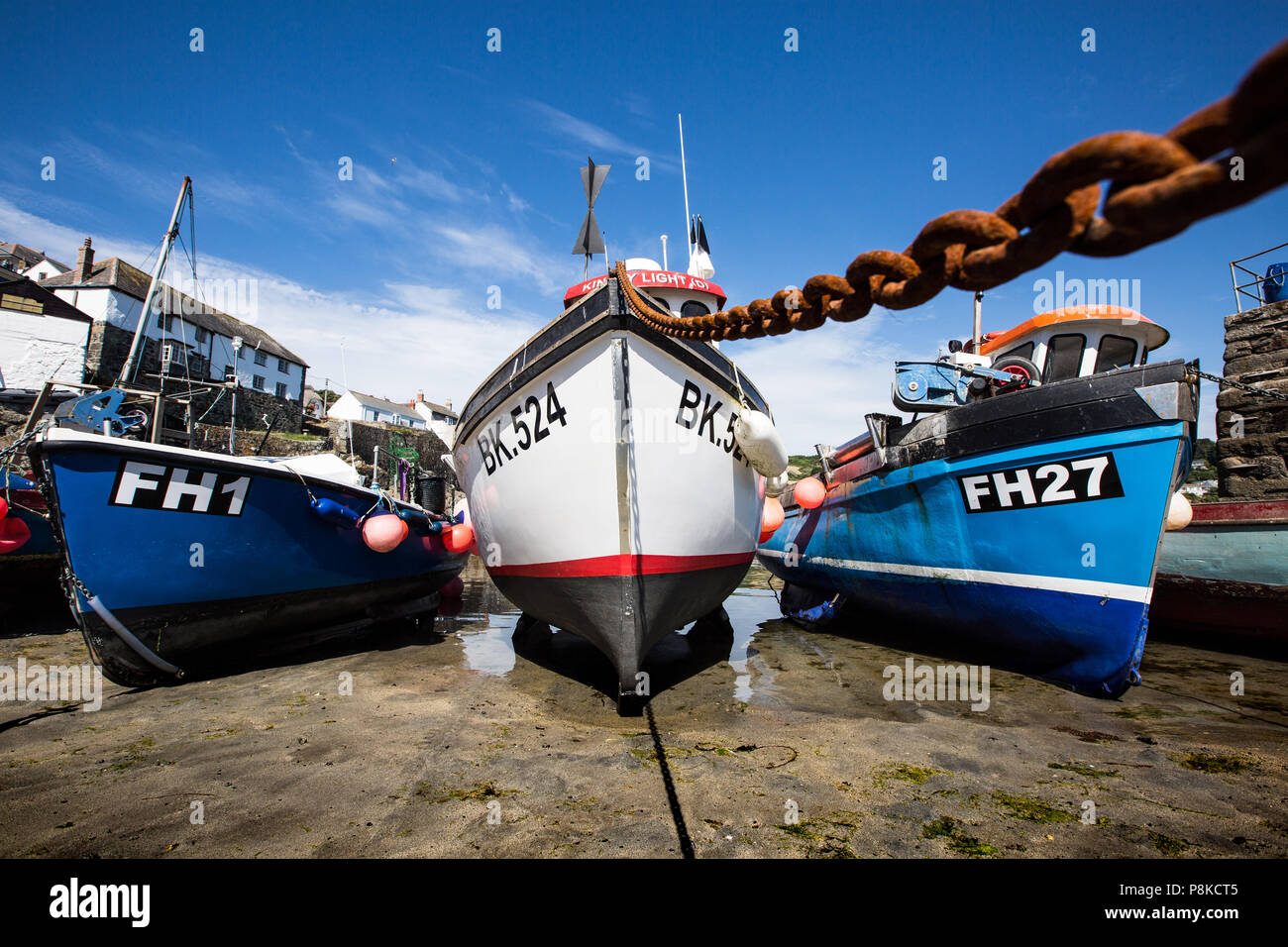 Les bateaux de pêche traditionnels des Cornouailles qui sont à sec et en attente de la marée pour entrer dans sur le sable de Coverack Harbour à Cornwall, UK. Banque D'Images