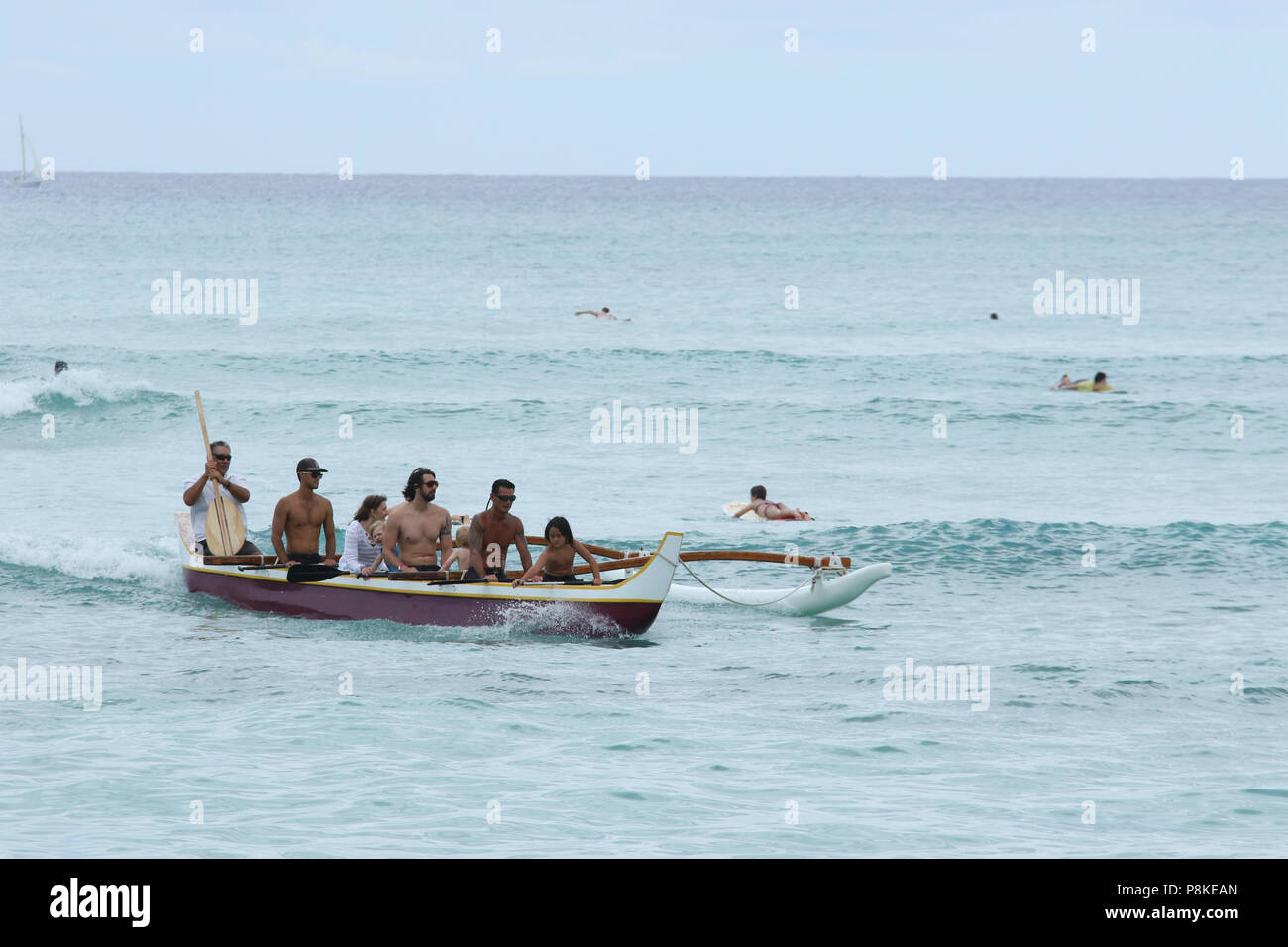 Manèges touristiques canoë. Les surfeurs et les gens dans l'eau sont visibles. La plage de Waikiki, Waikiki, Honolulu, Oahu, Hawaii, USA. Banque D'Images