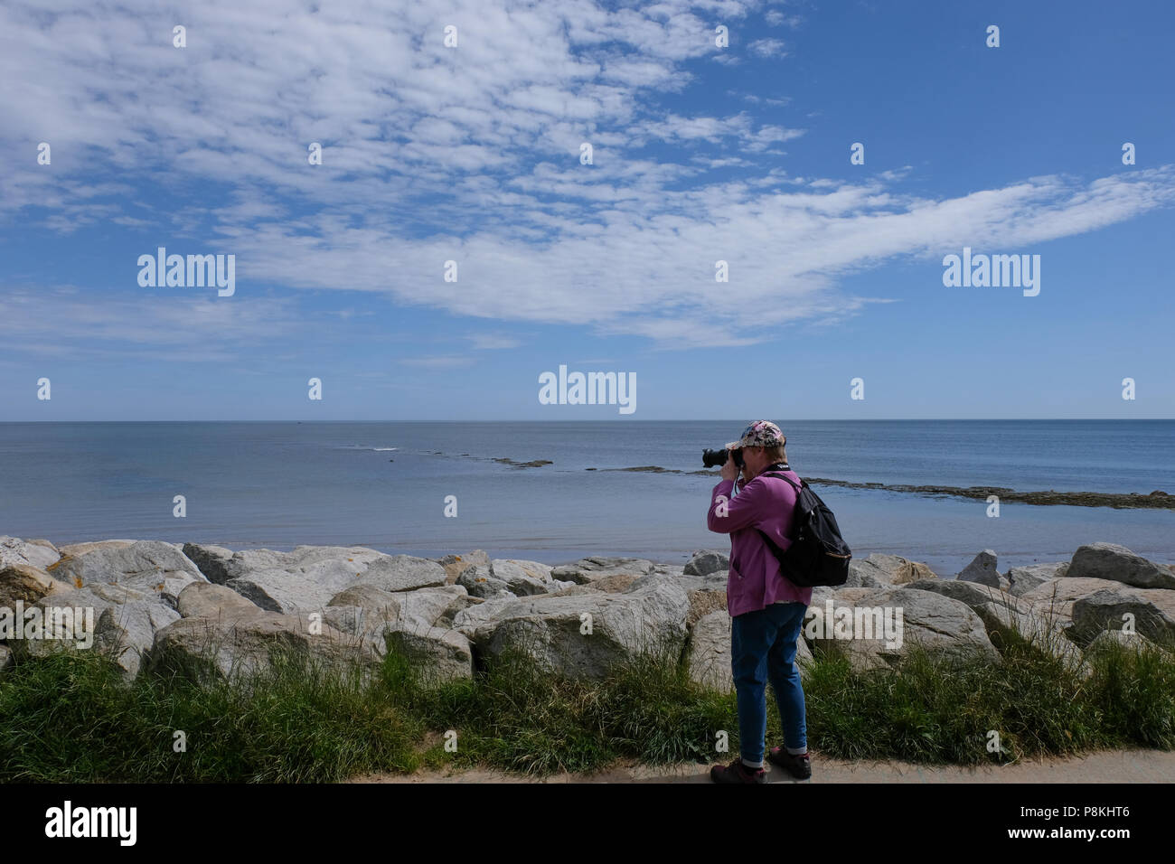 Des photos de photographe retraité dame en face de la paroi de la mer avec vue sur la mer et les rochers dans backgroundRobin,Hood's Bay Heritage Coast Yorkshire, Angleterre, Royaume-Uni Banque D'Images