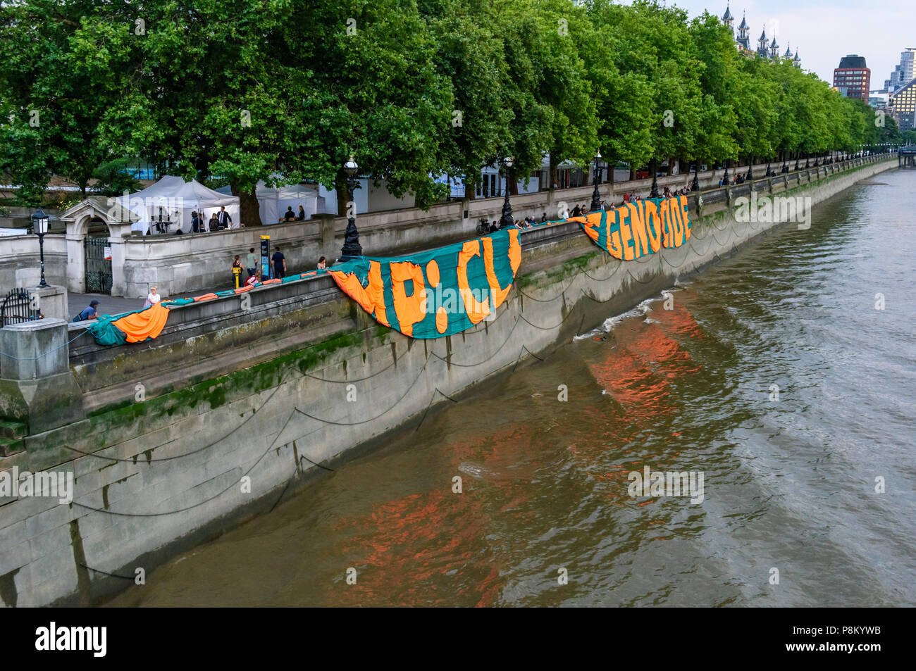 Londres, Royaume-Uni. 12 juillet 2018. Activistes du climat mark Trump à l'occasion de sa visite au Royaume-Uni en laissant tomber une bannière géante de 100 mètres de long sur la rivière mur de la Tamise en face du Palais de Westminster. La bannière a porté le message 'TRUMP : génocide climatique" en lettres orange fluorescent autour de 15m de haut. Ils disent qu'il est ignorant délibérément la science sur le changement climatique et menace l'existence même de la vie humaine sur terre en sapant si ce n'est pas renverser les nous et les efforts mondiaux pour lutter contre la plus grande menace que l'humanité fait face aujourd'hui, la déstabilisation catastrophique du climat mondial. Ses actions condamner bil Banque D'Images