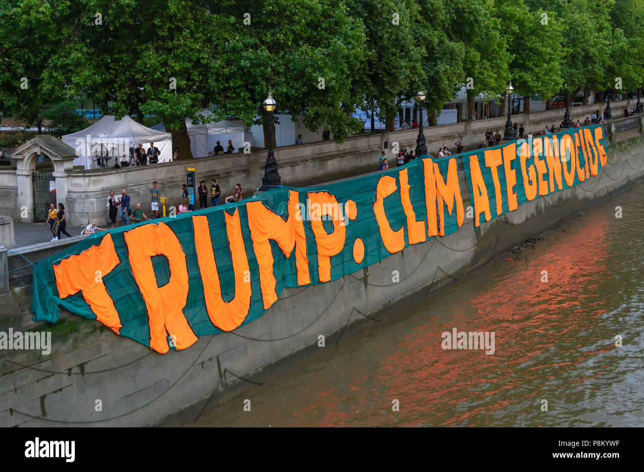 Londres, Royaume-Uni. 12 juillet 2018. Activistes du climat mark Trump à l'occasion de sa visite au Royaume-Uni en laissant tomber une bannière géante de 100 mètres de long sur la rivière mur de la Tamise en face du Palais de Westminster. La bannière a porté le message 'TRUMP : génocide climatique" en lettres orange fluorescent autour de 15m de haut. Ils disent qu'il est ignorant délibérément la science sur le changement climatique et menace l'existence même de la vie humaine sur terre en sapant si ce n'est pas renverser les nous et les efforts mondiaux pour lutter contre la plus grande menace que l'humanité fait face aujourd'hui, la déstabilisation catastrophique du climat mondial. Ses actions condamner bil Banque D'Images