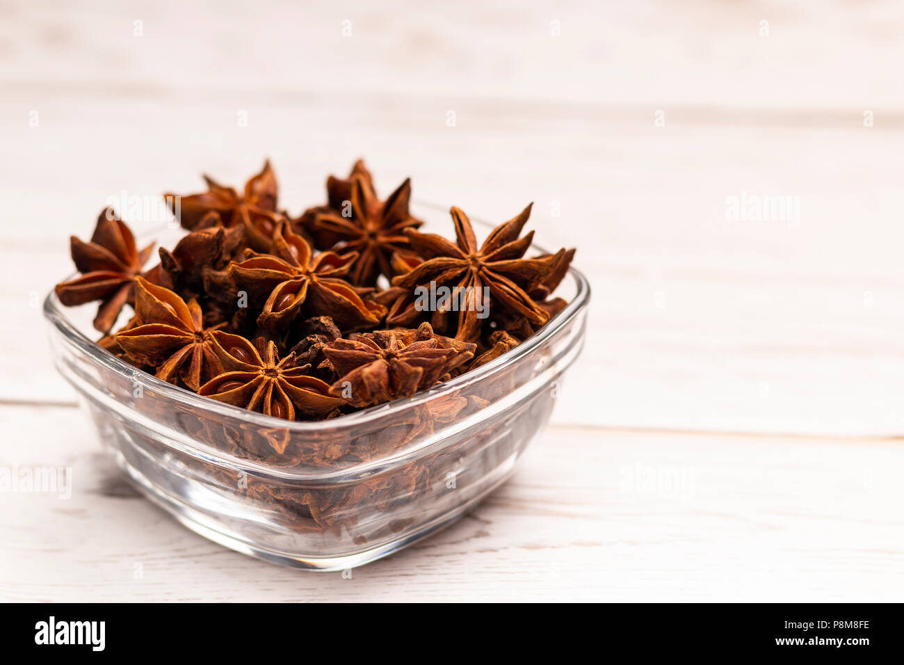 Close-up view of dry brown star anis en petit tableau blanc sur plaque de verre Banque D'Images