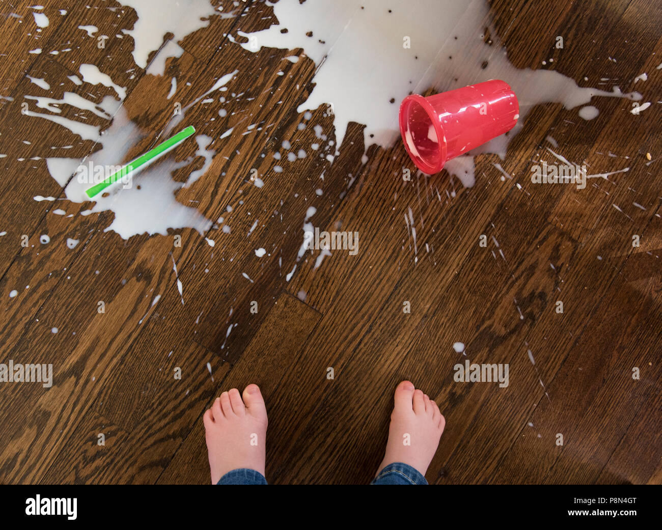 Les pieds du garçon par un milkshake renversé Banque D'Images