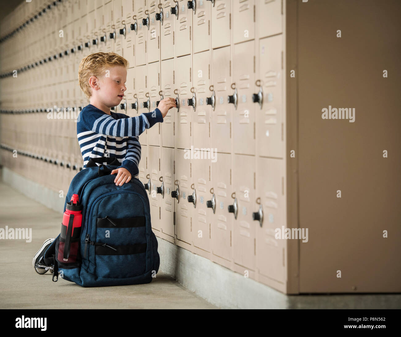 Garçon avec sac à dos près des casiers de l'école Banque D'Images