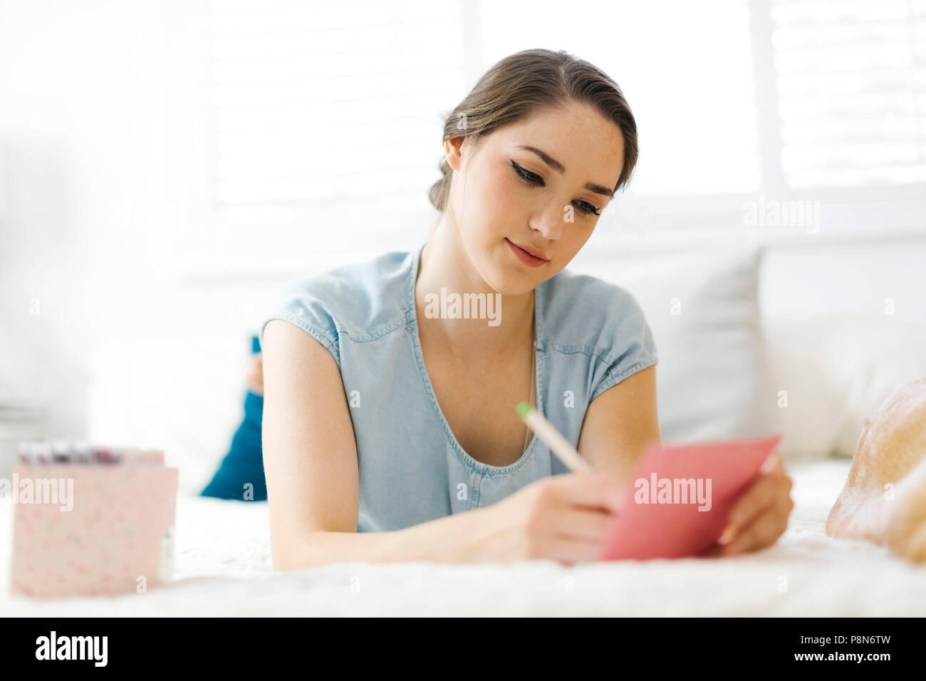 Femme écrivant en carte sur le lit Banque D'Images