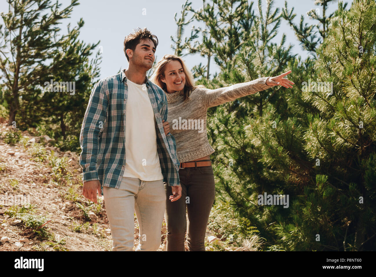 Young man and woman walking in mountain rail avec femme montrant une vue. Couple looking at a vue tout en randonnée dans la nature. Banque D'Images