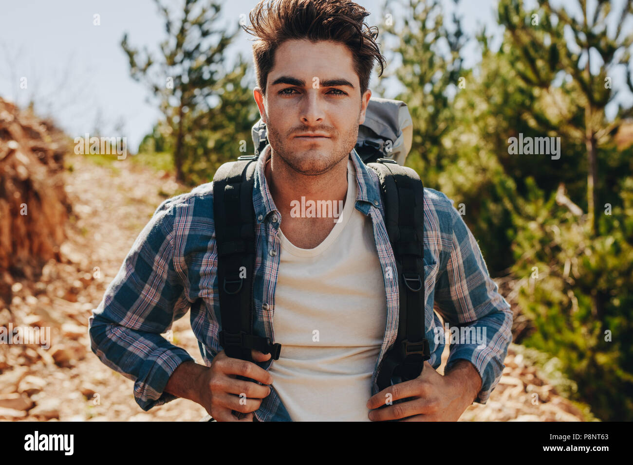 Beau jeune mec avec sac à dos en descendant la piste de montagne. Homme randonnée dans la nature sur une journée d'été. Banque D'Images