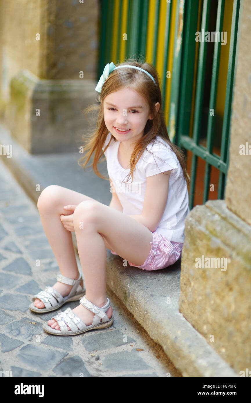 Adorable petite fille assise sur une porte sur l'été chaud et ensoleillé en  journée ville italienne typique Photo Stock - Alamy