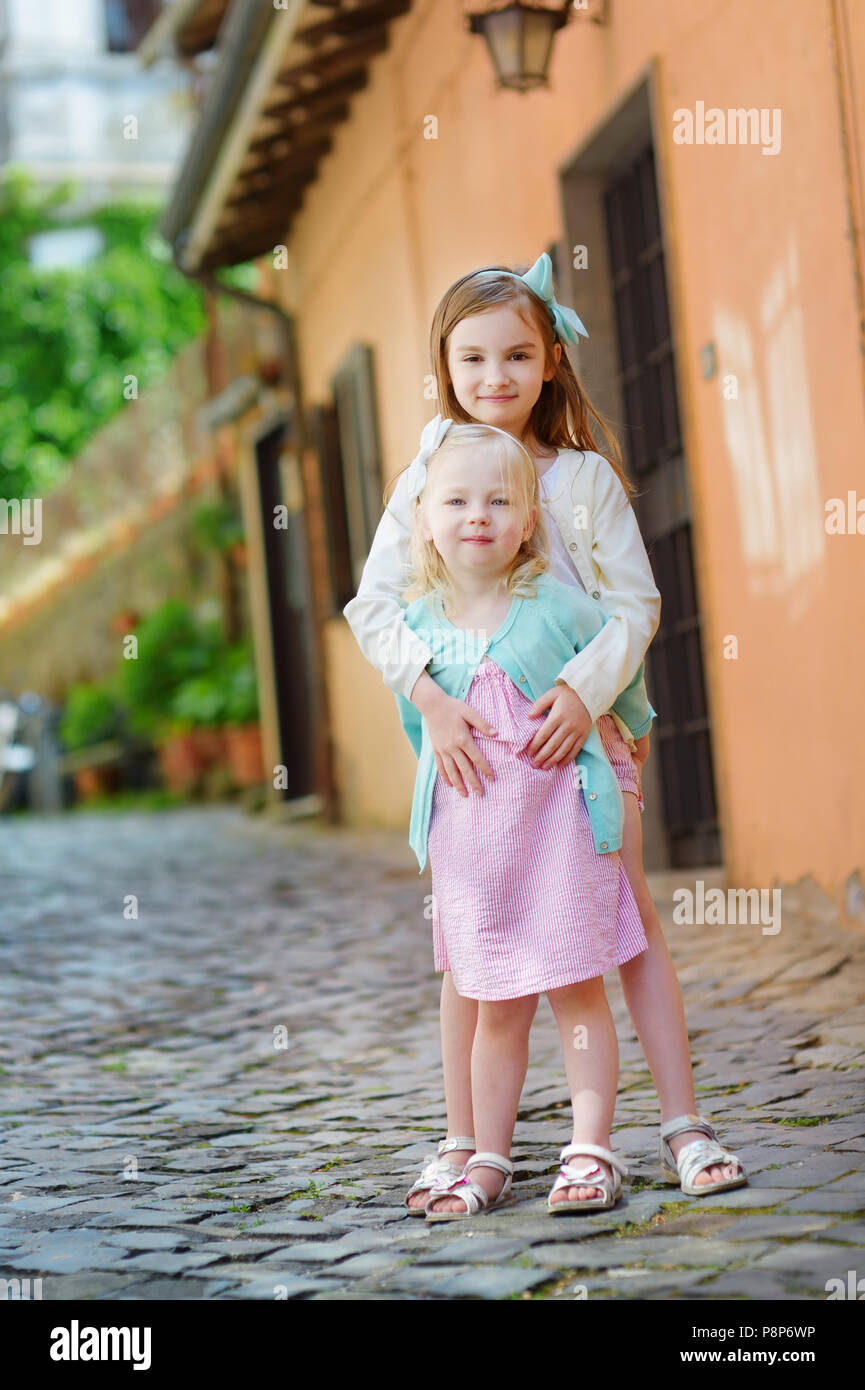 Deux adorables petites soeurs de rire et serrant le jour d'été chaud et ensoleillé dans la ville italienne Banque D'Images