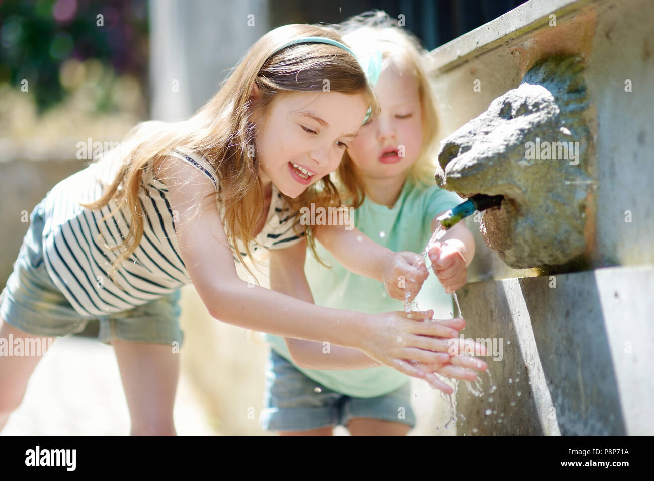 Deux sœurs s'amusant avec l'eau potable fontaine en Italie le jour d'été chaud et ensoleillé Banque D'Images