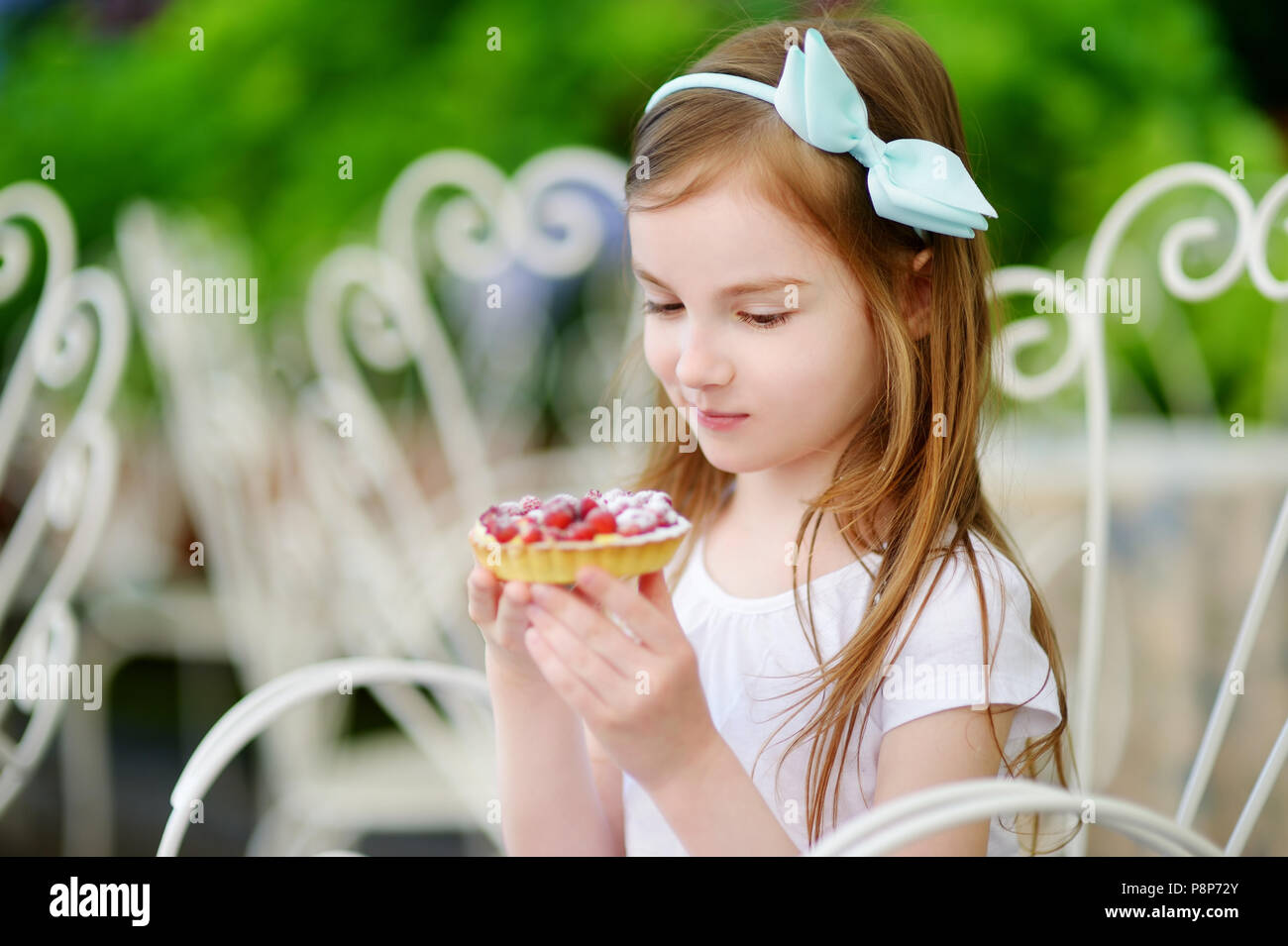 Adorable petite fille fraîche sweet strawberry cake à l'extérieur, sur l'été chaud et ensoleillé jour en Italie Banque D'Images