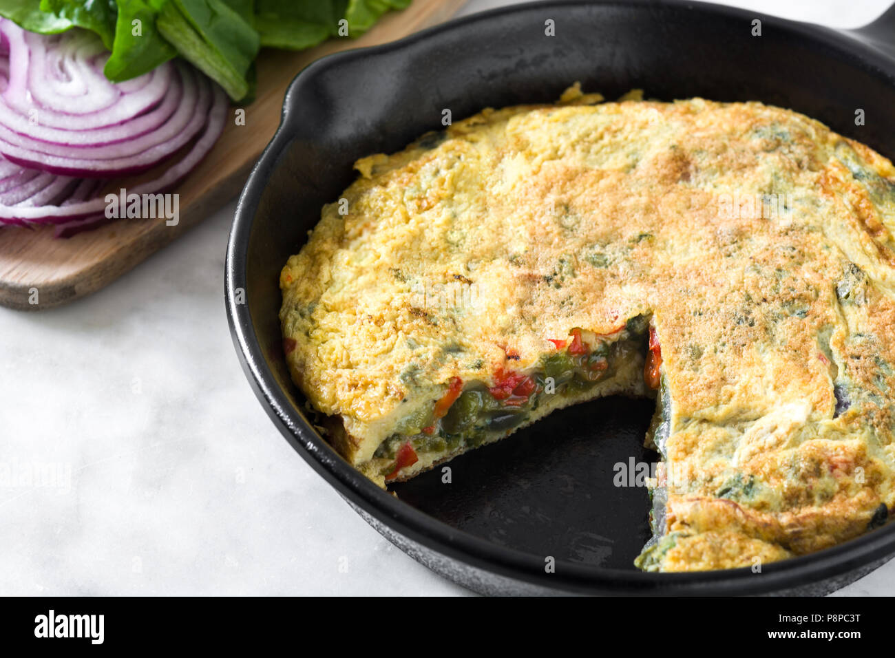 Faites de la frittata des œufs et des légumes dans une poêle de fer, sur le marbre blanc Banque D'Images