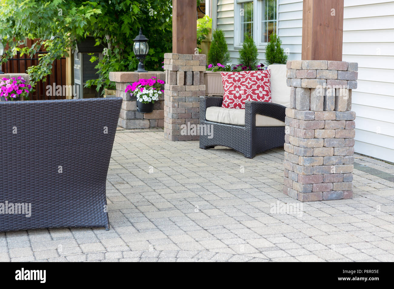 Pergola en bois élégant ornement jambes avec revêtement en brique sur un patio pavé avec des meubles de jardin et de fleurs colorées Banque D'Images