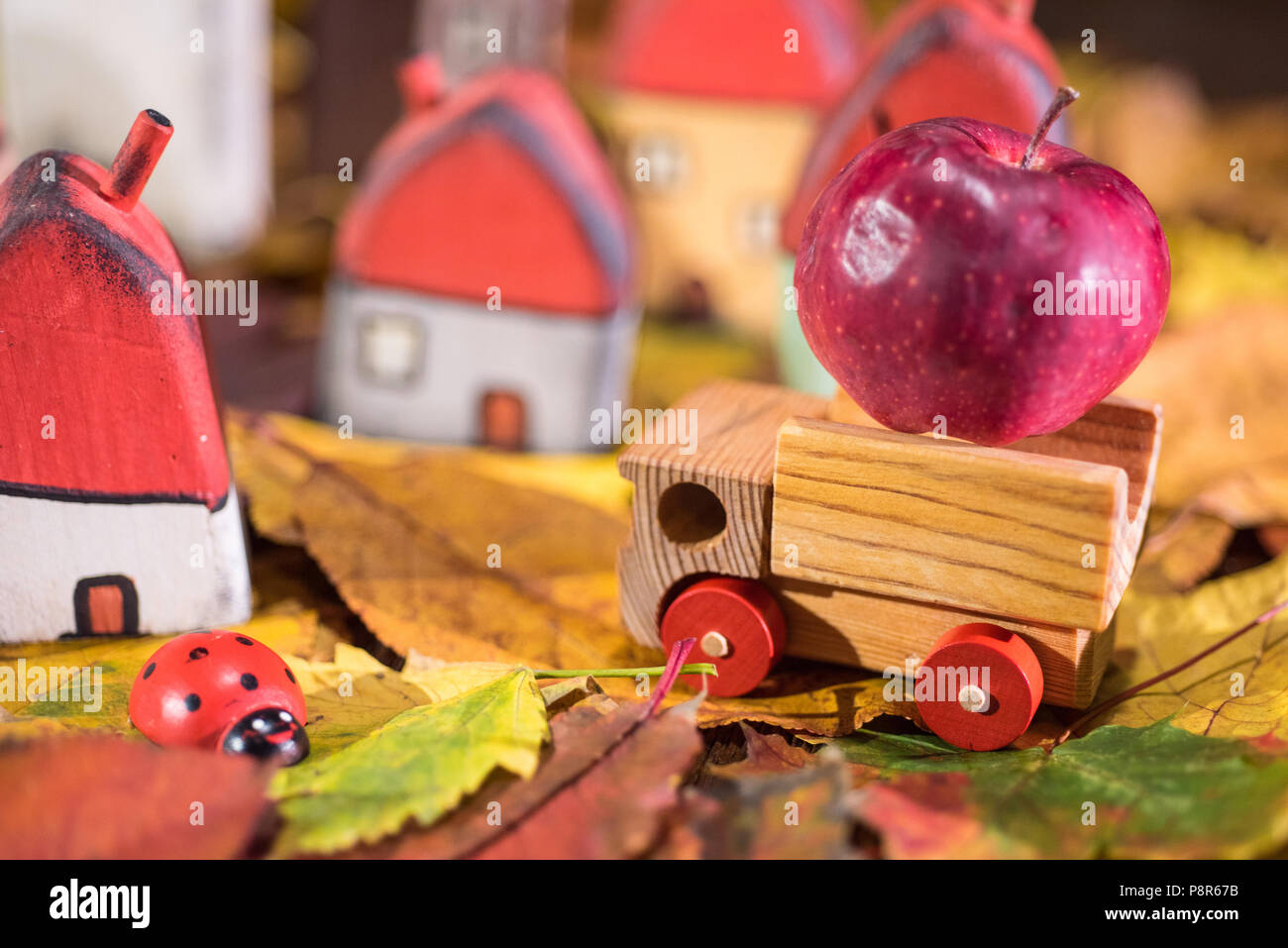 Aire de jeux pour les enfants, l'arrangement de jouet peint les maisons en bois, camion transportant une pomme, coccinelle sur les feuilles d'automne. Concept de la petite enfance Banque D'Images