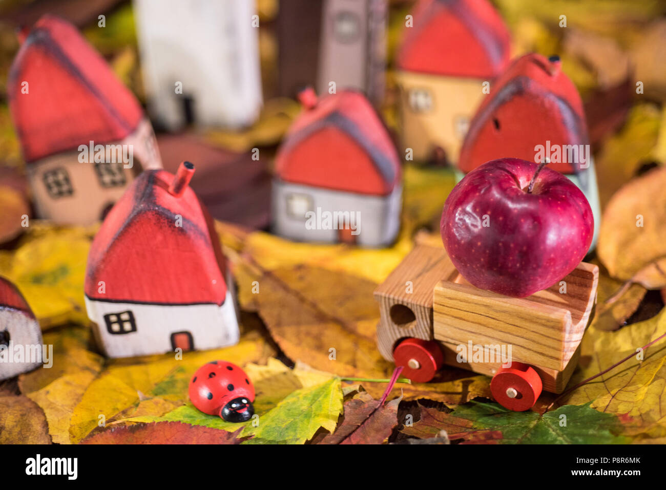 Aire de jeux pour les enfants, l'arrangement de jouet peint les maisons en bois, camion transportant une pomme, coccinelle sur les feuilles d'automne. Concept de la petite enfance Banque D'Images