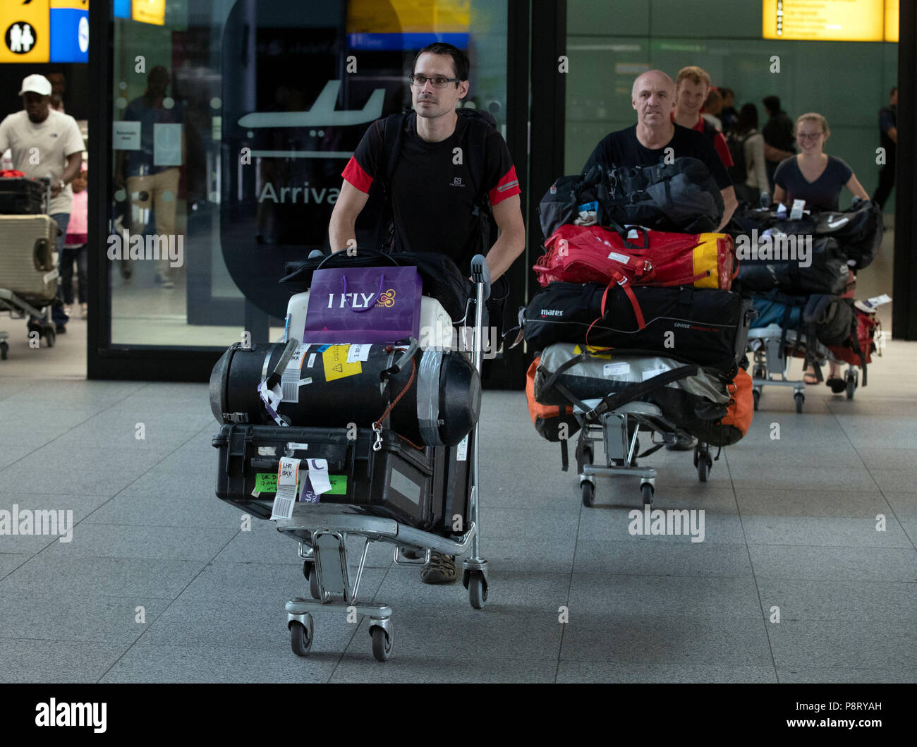 Diver Chris Jewell, gauche, à partir de la mission de sauvetage, ce qui a contribué à sauver 12 écoliers et leur entraîneur de football à partir d'une grotte inondée en Thaïlande, arrive retour à l'aéroport d'Heathrow à Londres. Banque D'Images