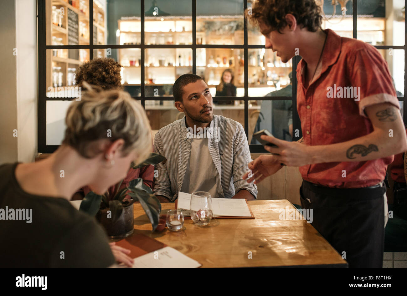 Amis assis dans un restaurant de l'alimentation commande de serveur Banque D'Images