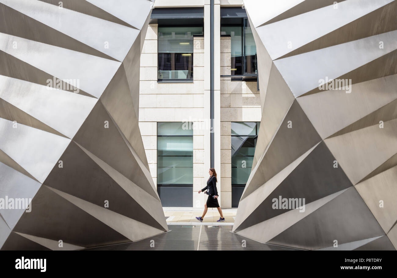 Femme marche entre les évents Paternoster (Angels Wings) sculpture en acier inoxydable par Thomas Heatherwick sur Ave Maria Lane, Ludgate Hill, Londres Banque D'Images