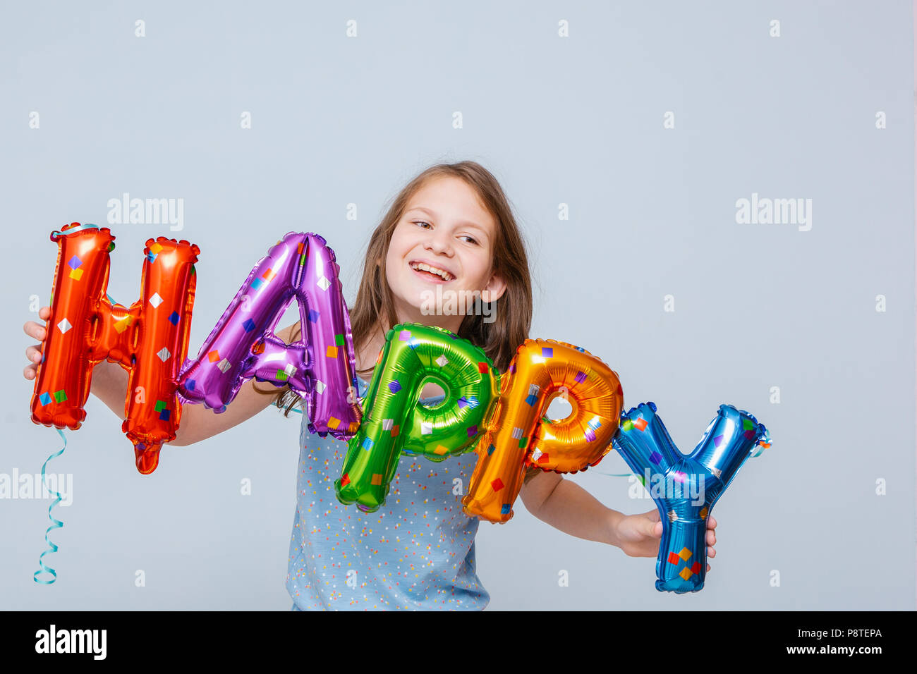 Cheerful girl avec des ballons anniversaire lettres Banque D'Images
