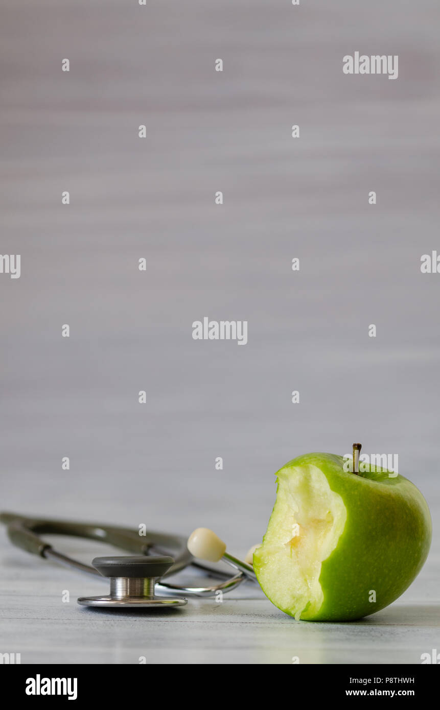 Frais vert pomme avec un morceau isolé et stéthoscope sur fond de bois blanc Banque D'Images