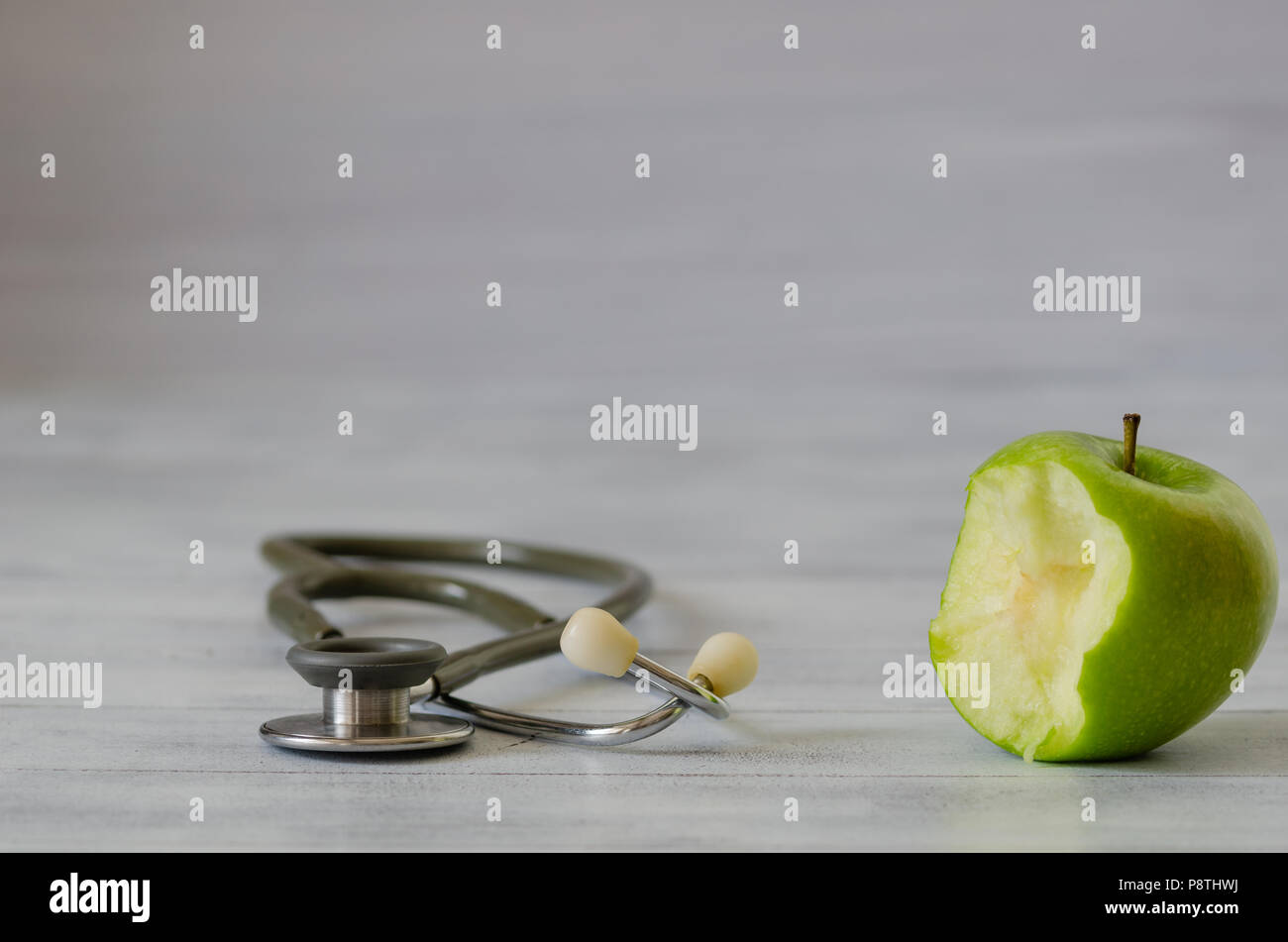 Frais vert pomme avec un morceau isolé et stéthoscope sur fond de bois blanc Banque D'Images