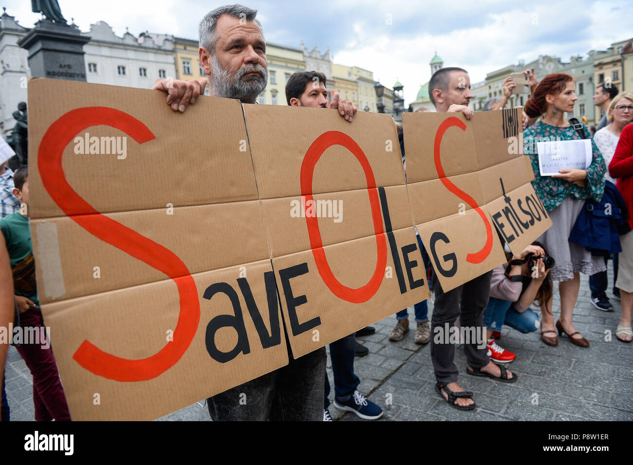 Cracovie, Pologne. Le 13 juillet, 2018. Un homme tient une bannière disant Sauver Oleg Sentsov.au cours de la manifestation de protestation exigeant la libération du cinéaste et écrivain ukrainien, Oleg Sentsov à la place principale de Cracovie qui a été condamné à 20 ans pour complot en vue de commettre des actes de terreur. Credit : Omar Marques/SOPA Images/ZUMA/Alamy Fil Live News Banque D'Images