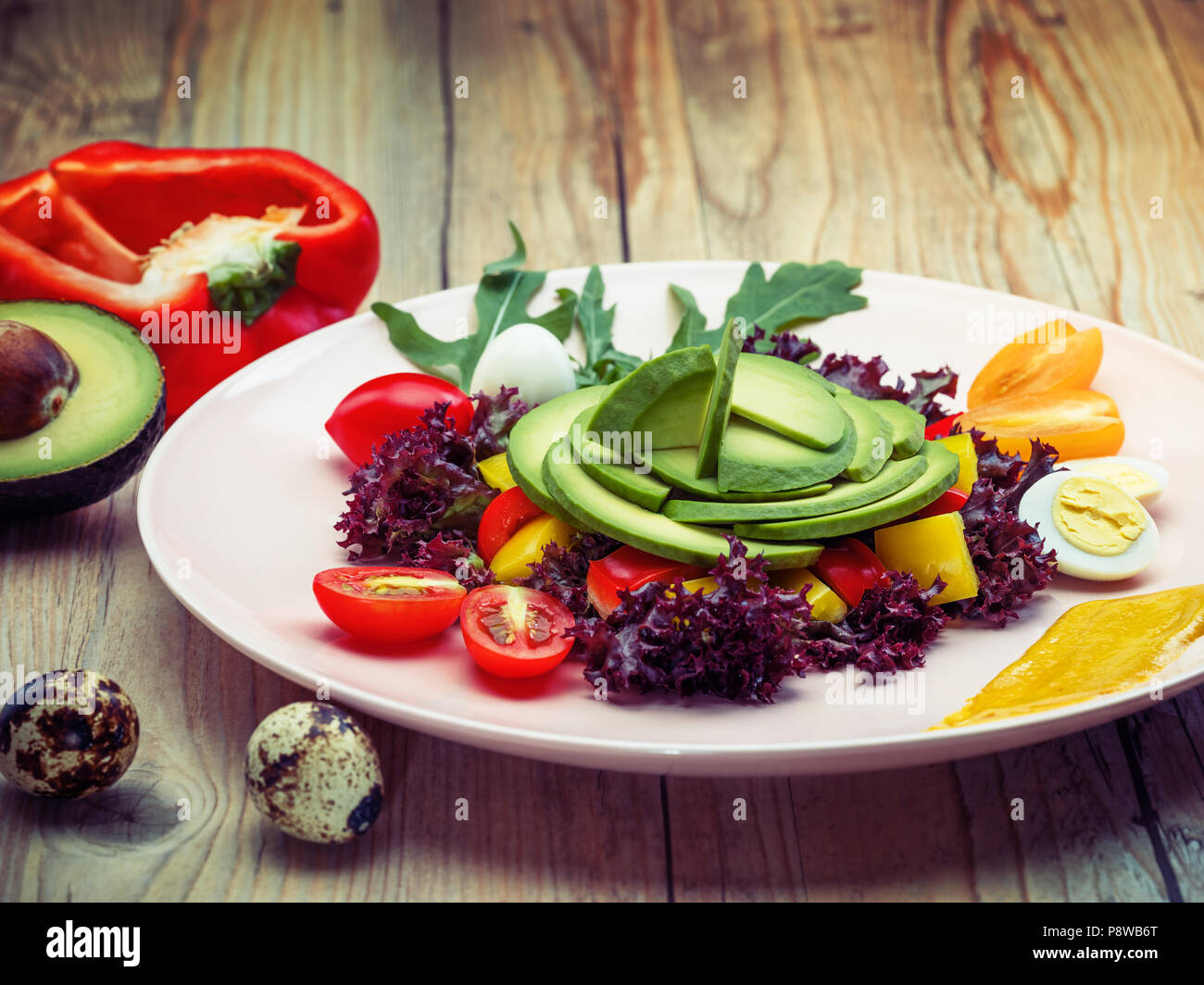 Salade d'alimentation avec des tomates cerises, des oeufs de cailles, jaune et le poivron rouge et la laitue. L'avocat est source de nutrition, de vitamines. Studio shot. Banque D'Images