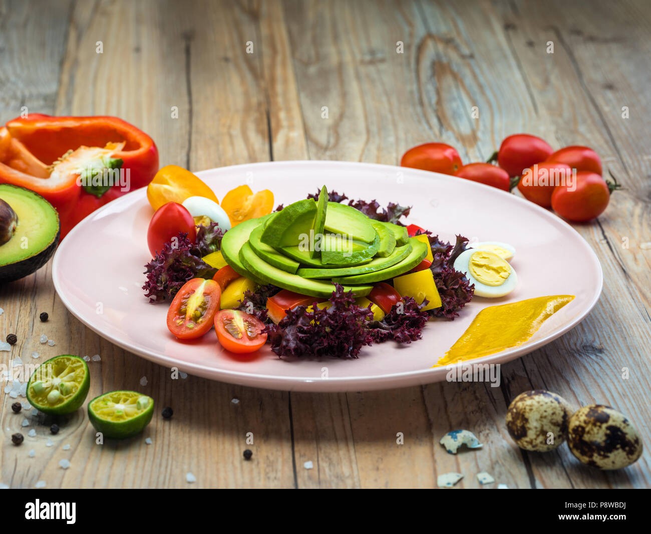 Salade d'alimentation avec des tomates cerises, des oeufs de cailles, jaune et le poivron rouge et la laitue. L'avocat est source de nutrition, de vitamines. Studio shot. Banque D'Images