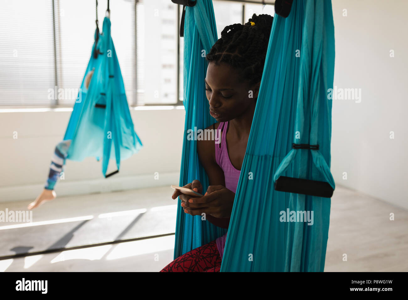 Woman using mobile phone while sitting on swing sling hamac Banque D'Images