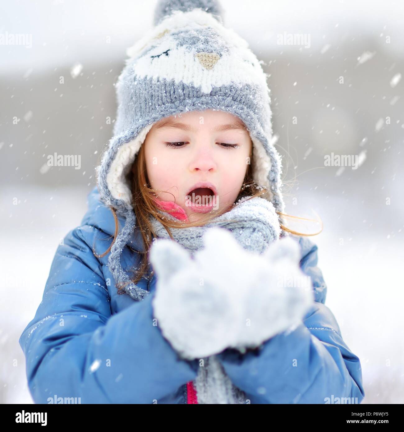 Funny little girl attraper des flocons avec sa langue dans le magnifique parc de neige pendant l'hiver Banque D'Images