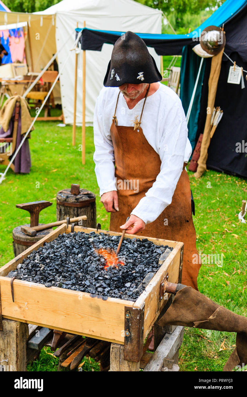 L'histoire vivante, une reconstitution d'un événement. L'homme médiéval, forgeron, à l'aide de forge pour faire des armes de fer, holding longueur de métal. Banque D'Images