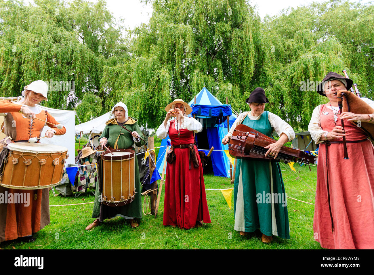 Reconstitution de l'histoire de vie médiévale événement. Les femmes voyageant de bande de ménestrels se tenant dans la ligne jouant d'un instrument à l'extérieur. Banque D'Images