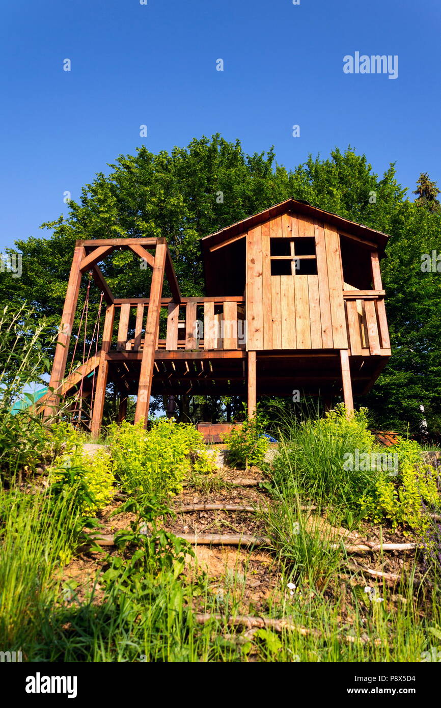 Beaux enfants playhouse en bois avec swing et faites glisser sur la colline Banque D'Images