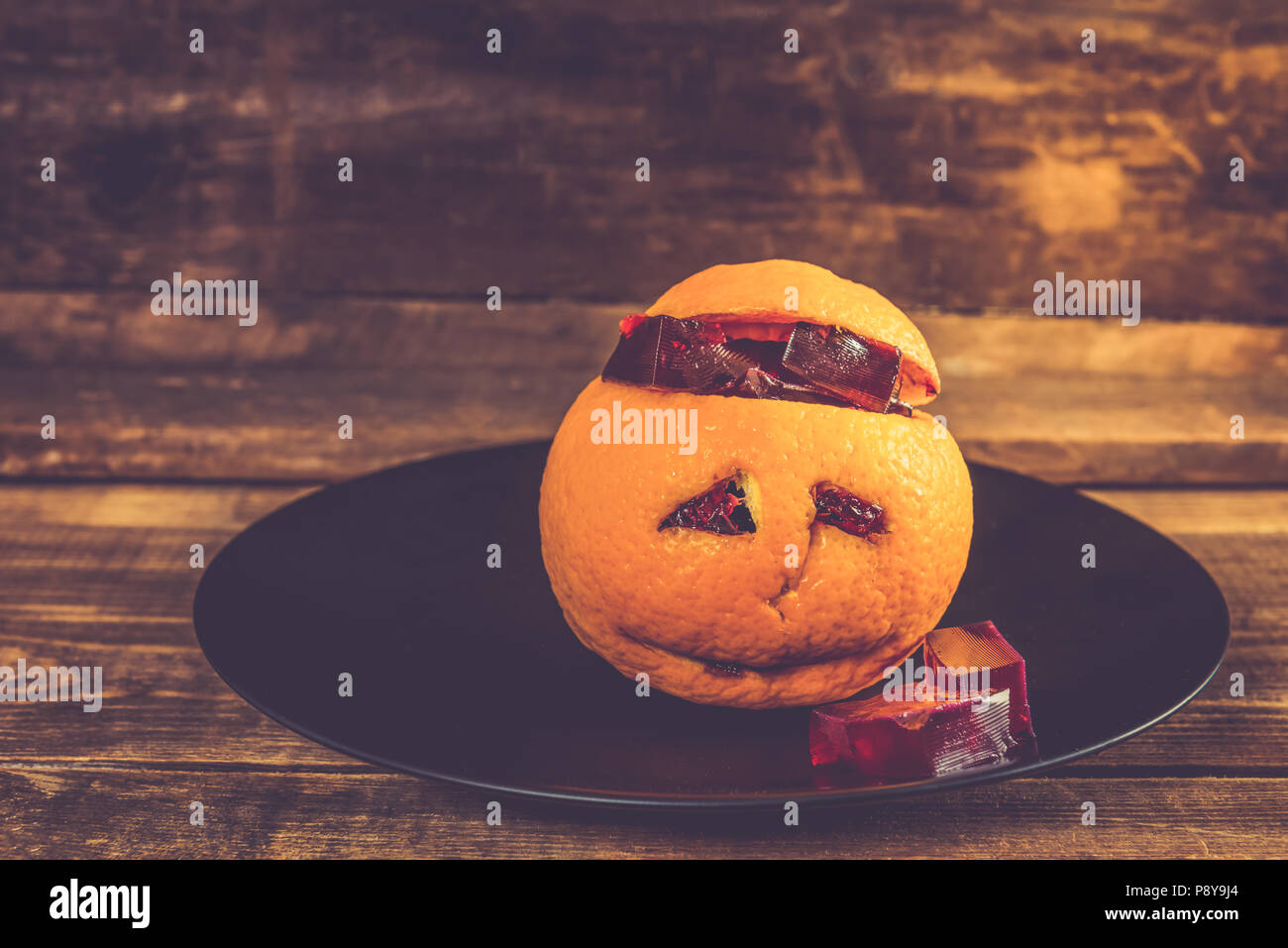 Kids Halloween set de table avec la gelée meurtrière, qui est servi à l'intérieur de l'orange avec visage triste Banque D'Images