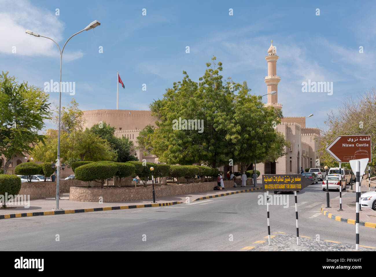 Ancien salon de Nizwa dans l'ouest de l'Oman avec murs de château / qasr visibles le long avec les gens et les voitures Banque D'Images