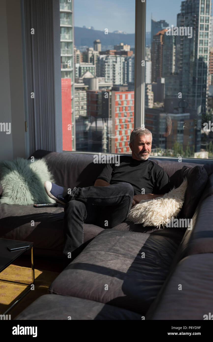 Man relaxing in living room à la maison Banque D'Images