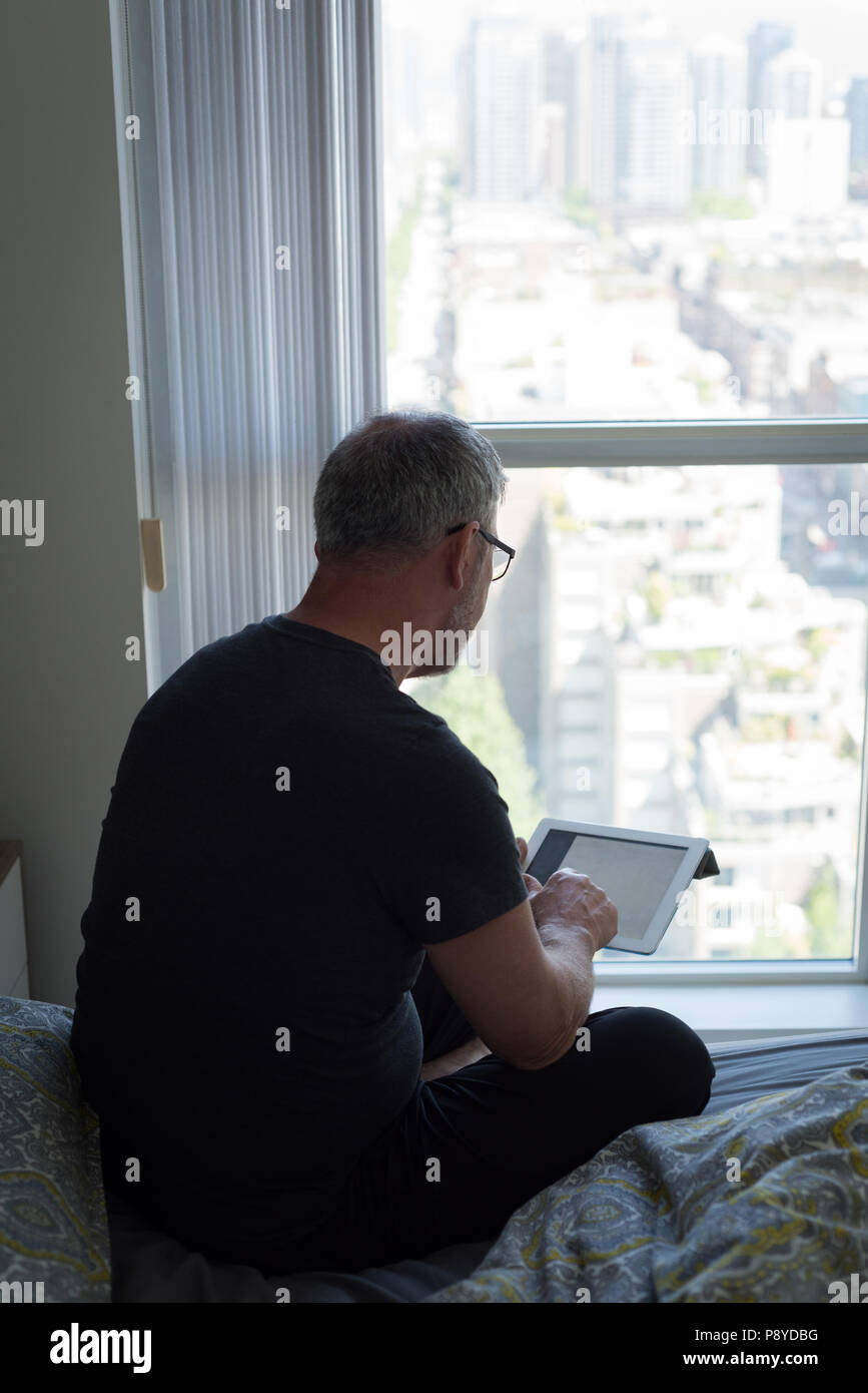 Man using digital tablet in chambre à la maison Banque D'Images