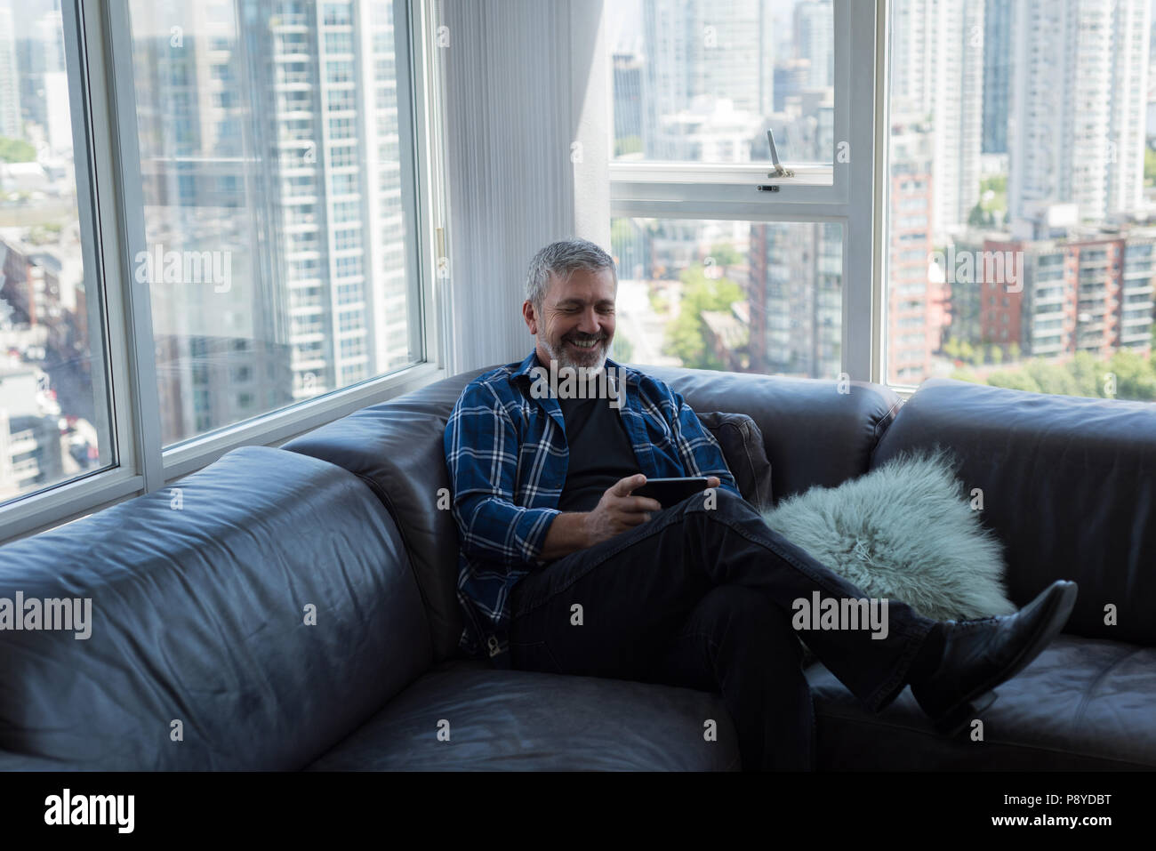 Man using digital tablet in living room Banque D'Images