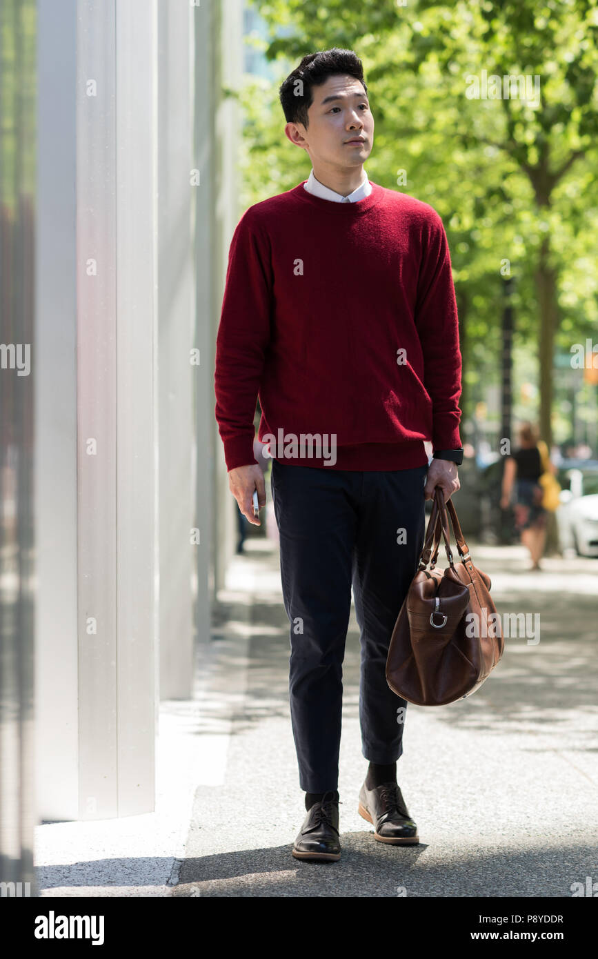 Homme qui marche sur le trottoir avec un sac Banque D'Images